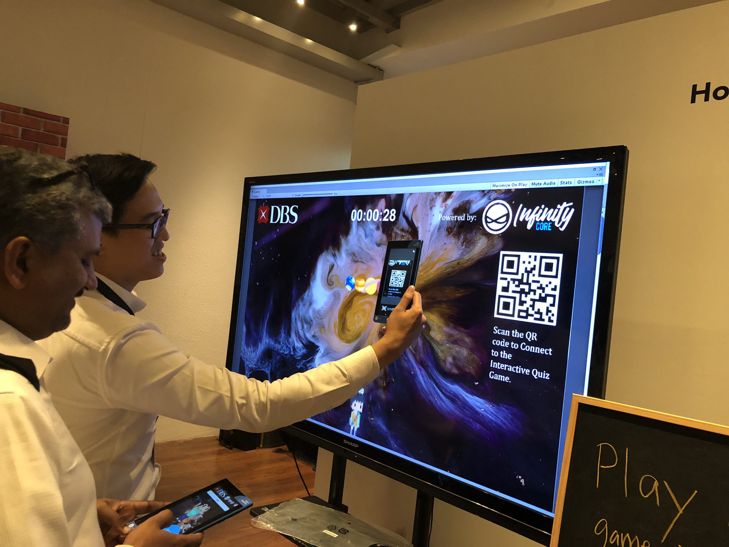 A man scans a code on the LED screen to connect his device to the interactive quiz game at the DBS immersion day event