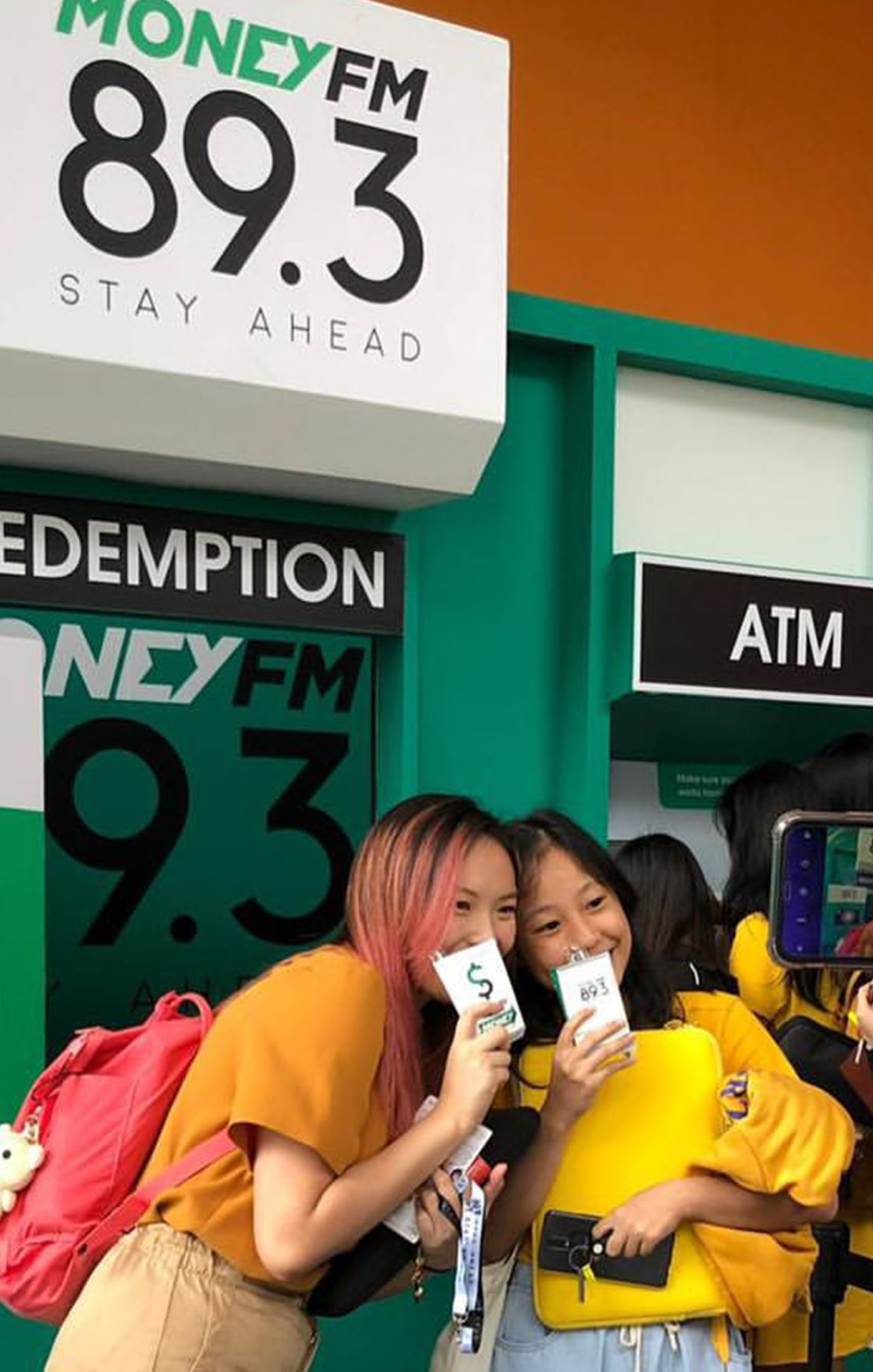 Two girls posing in front the MoneyFM Interactive ATM 2in1 Game Kiosk