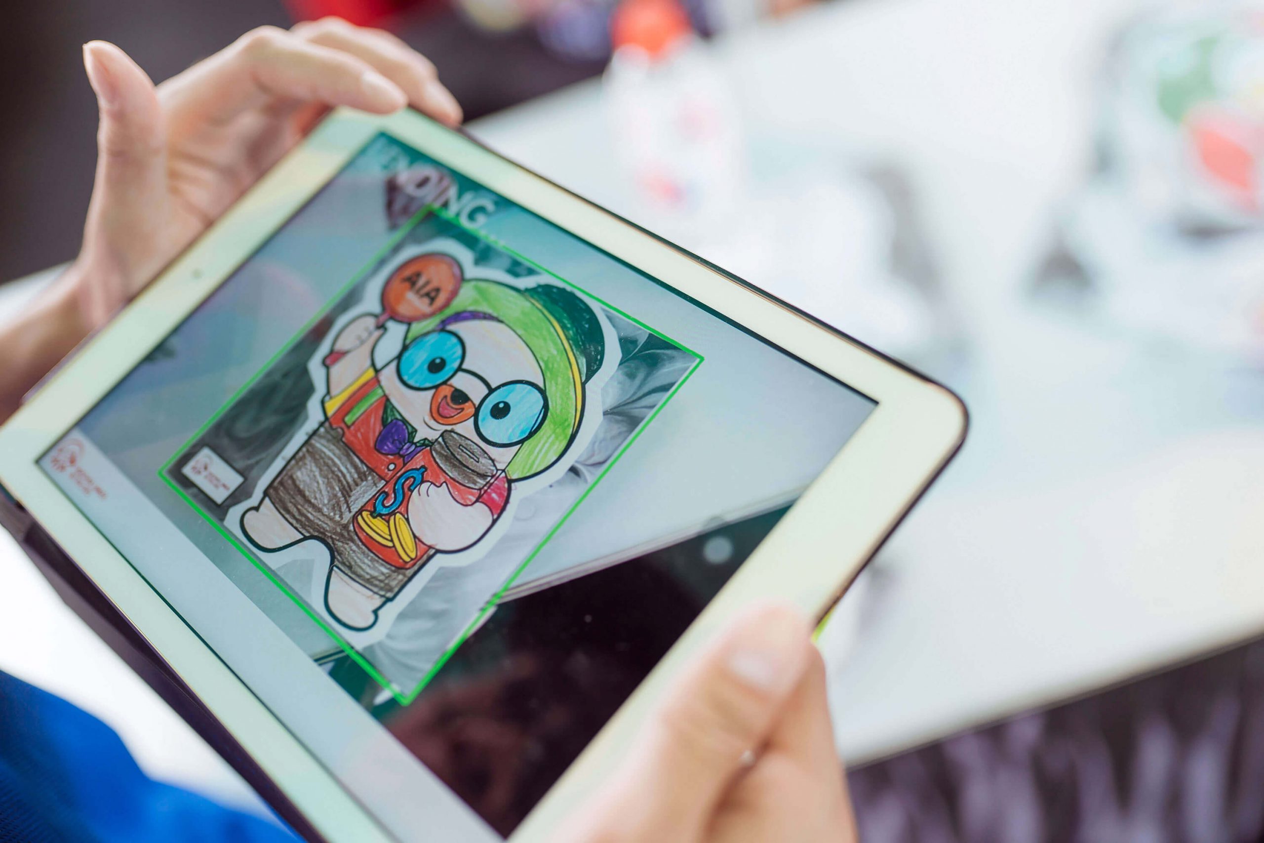 Scanning a colored AIA family mascot with an AR application, which will then be sent to the large LED Wall where it is looped and played throughout the event