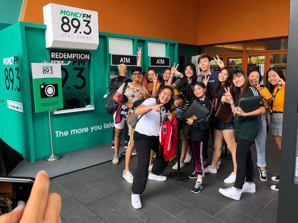 A group of youngsters posing for a picture enthusiastically in front of the MoneyFM Interactive ATM 2in1 Game Kiosk