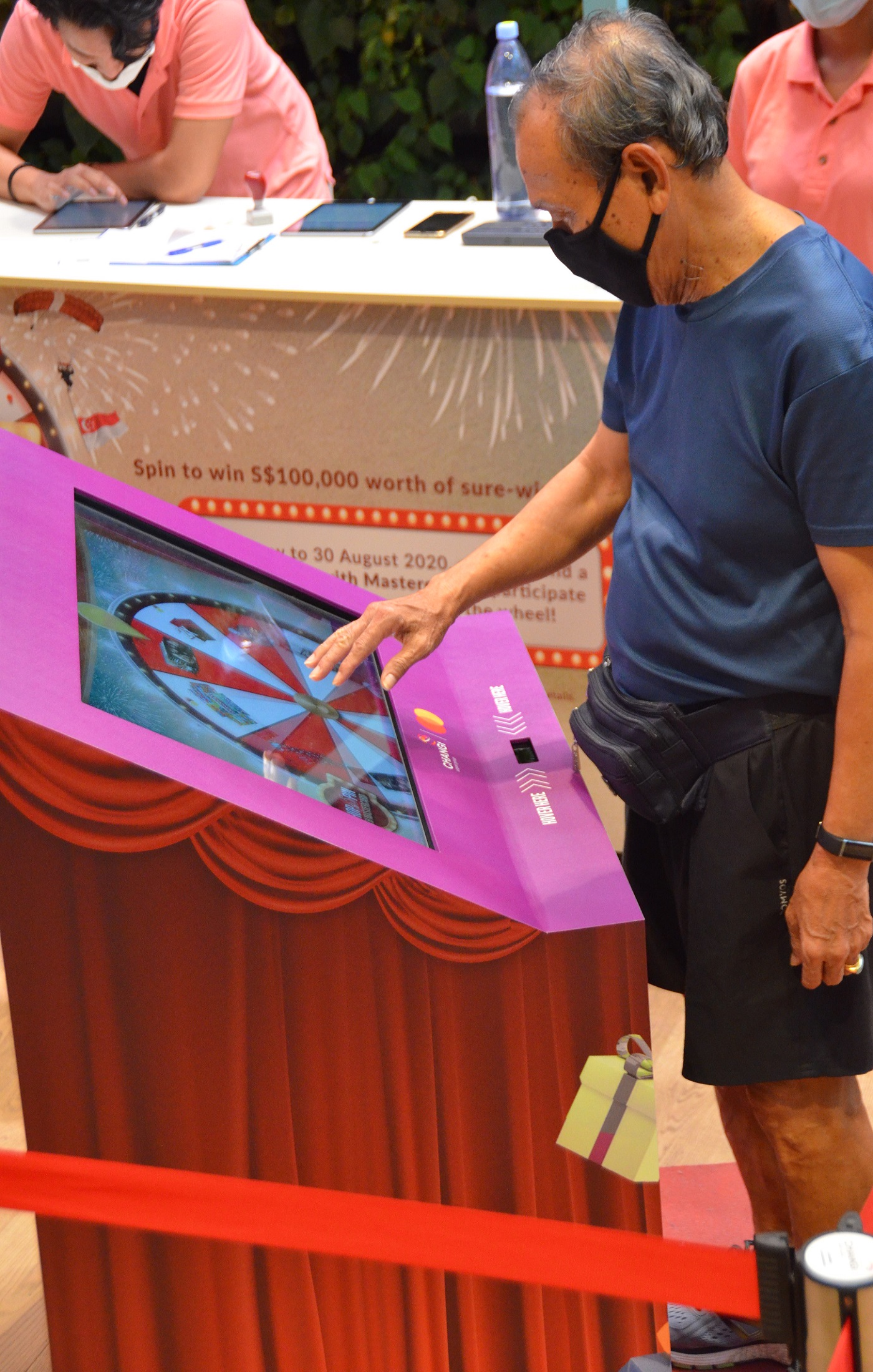 An elderly man interacting with the Changi Airport Group Contactless shop and spin lucky draw system